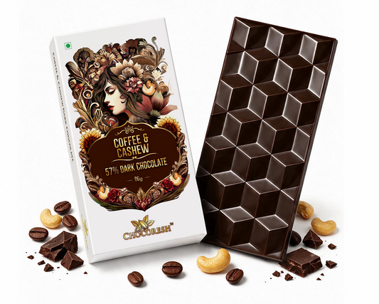 A bar of chocolate and its decorative packaging box on a white background, with scattered chocolate pieces, coffee beans, and cashews around them. The box reads 'Coffee & Cashew 5% Dark Chocolate' and shows an ornate illustrated label.